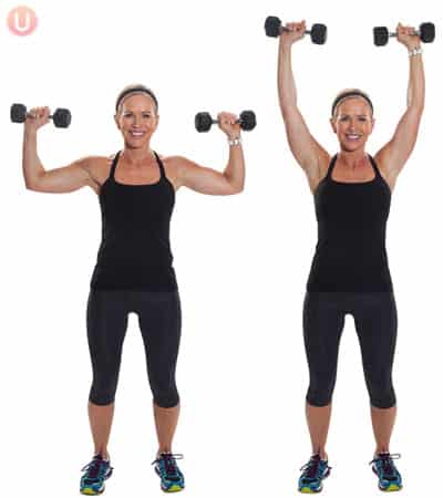 Chris Freytag doing an overhead shoulder press with black dumbbells. 