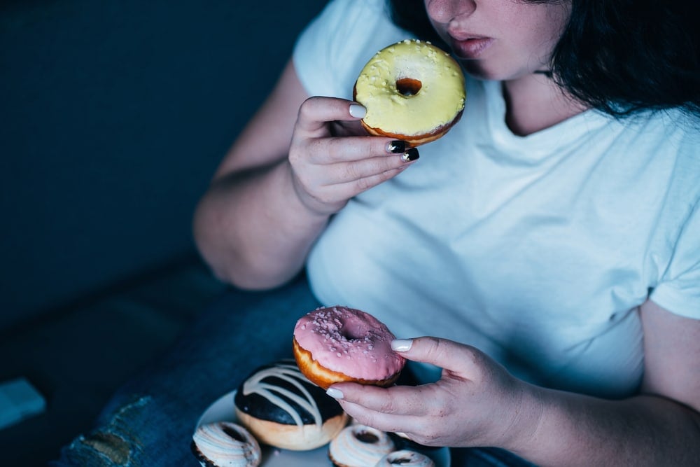 Woman in blue shirt eating a donut.